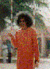 Sathya Sai Baba standing, holding hand up, facing